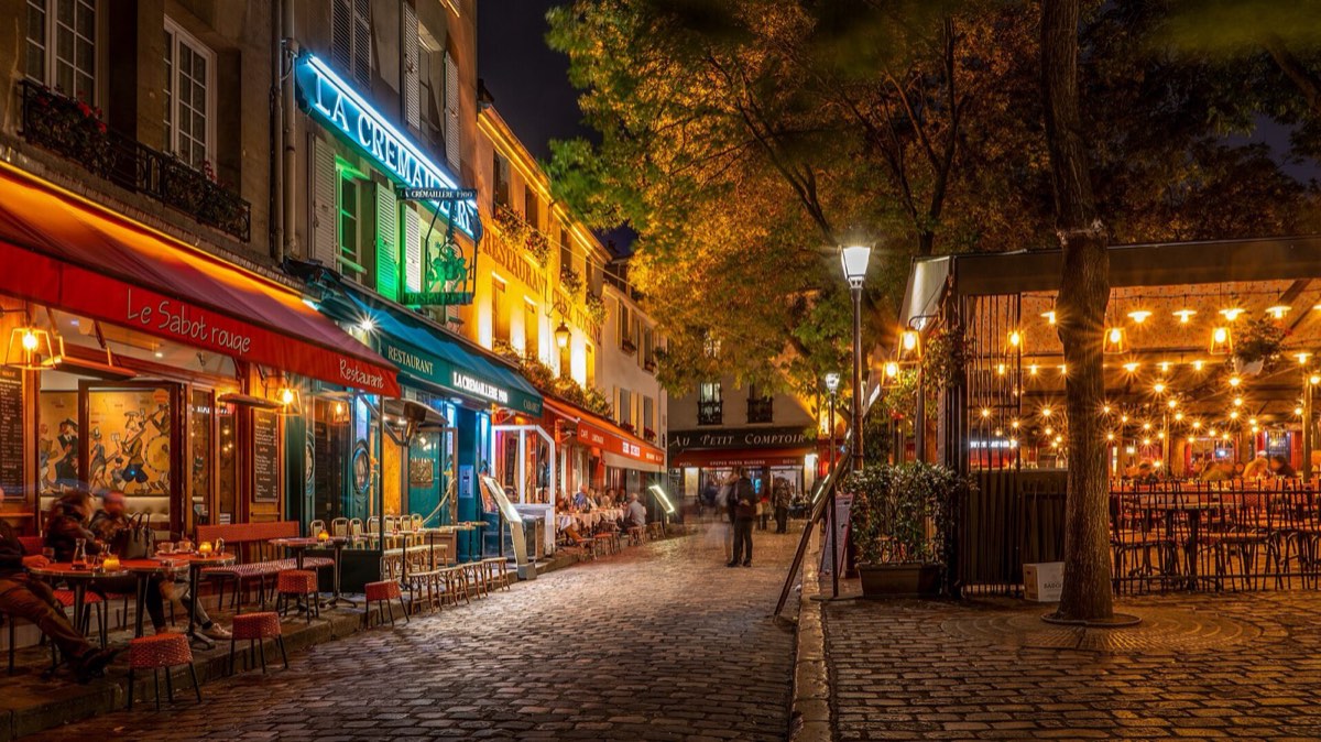 Terrasses de restaurants illuminées place du Tertre, le soir